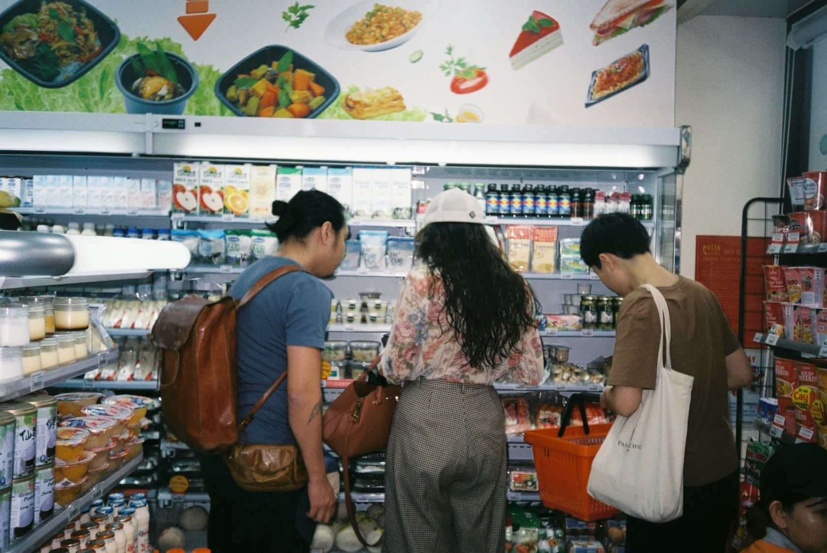 ein Gruppe Menschen steht vor einen Kühlregal im Supermarkt
